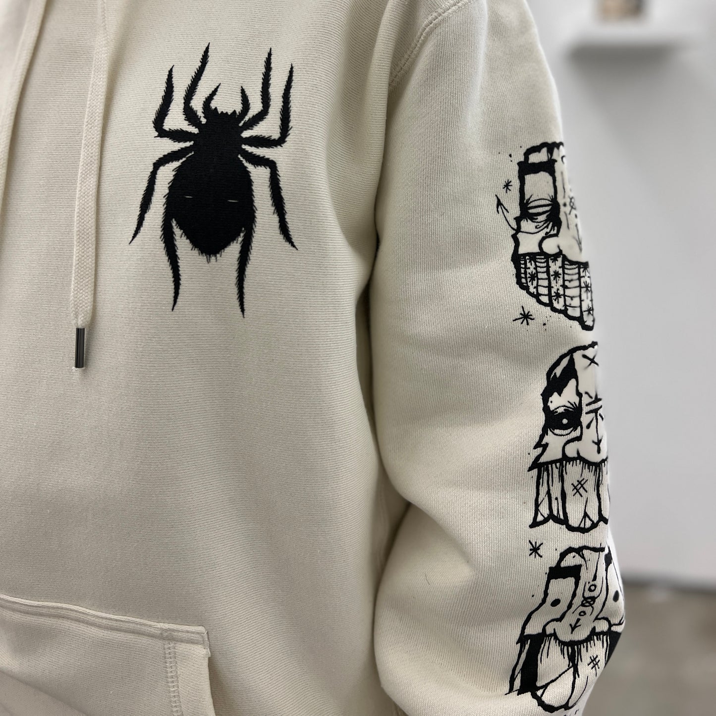  by GATS titled GATS - "Arachnophile" Hooded Sweatshirt in Bone