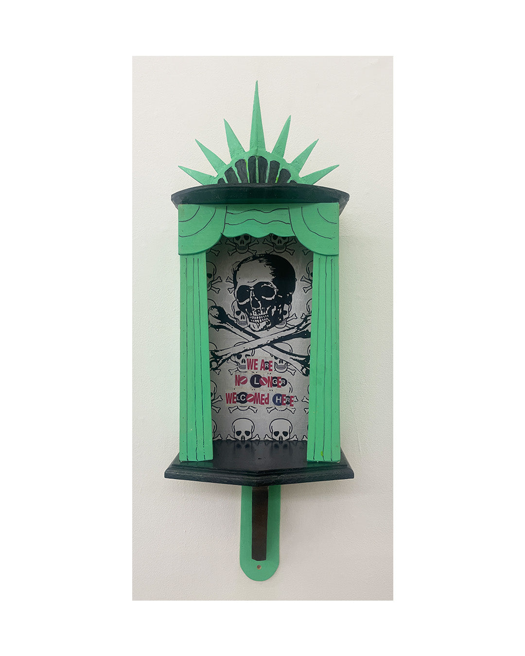 Decorative wall shelf with green and black design featuring skulls and crossbones on a white background.