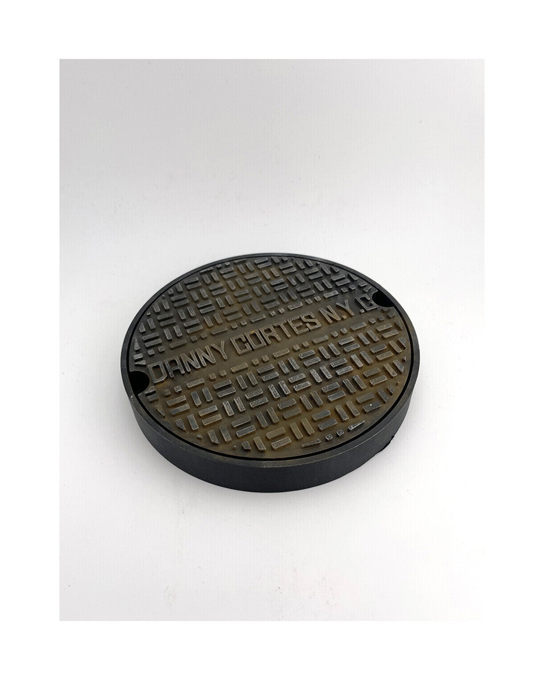 Round black and brown textured coaster with 'Danny Gorten' branding on a white background